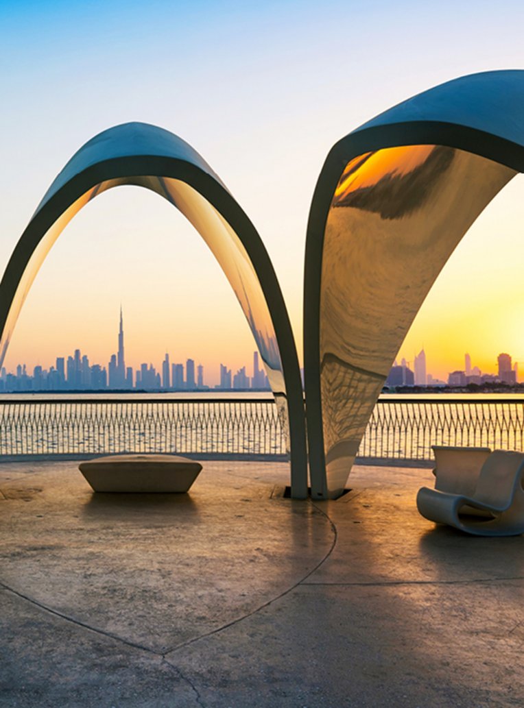 Blick auf die Stadt Dubai durch ein grosses Torbogen, das die moderne Architektur und den Himmel zeigt.