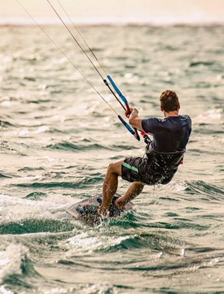 Ein Mann surft auf dem Wind in den Wellen des Ozeans vor der Küste von Mauritius.