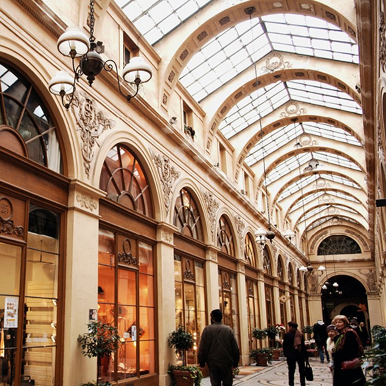 Ein grosses Gebäude in Paris mit vielen Menschen, die geschäftig umherlaufen.