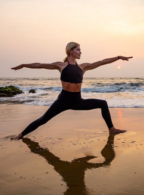 Frau praktiziert Yoga am Strand während des Sonnenuntergangs auf den Seychellen.