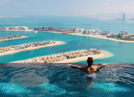 Eine Frau sitzt in einem Pool mit Blick auf den Ozean in Dubai.
