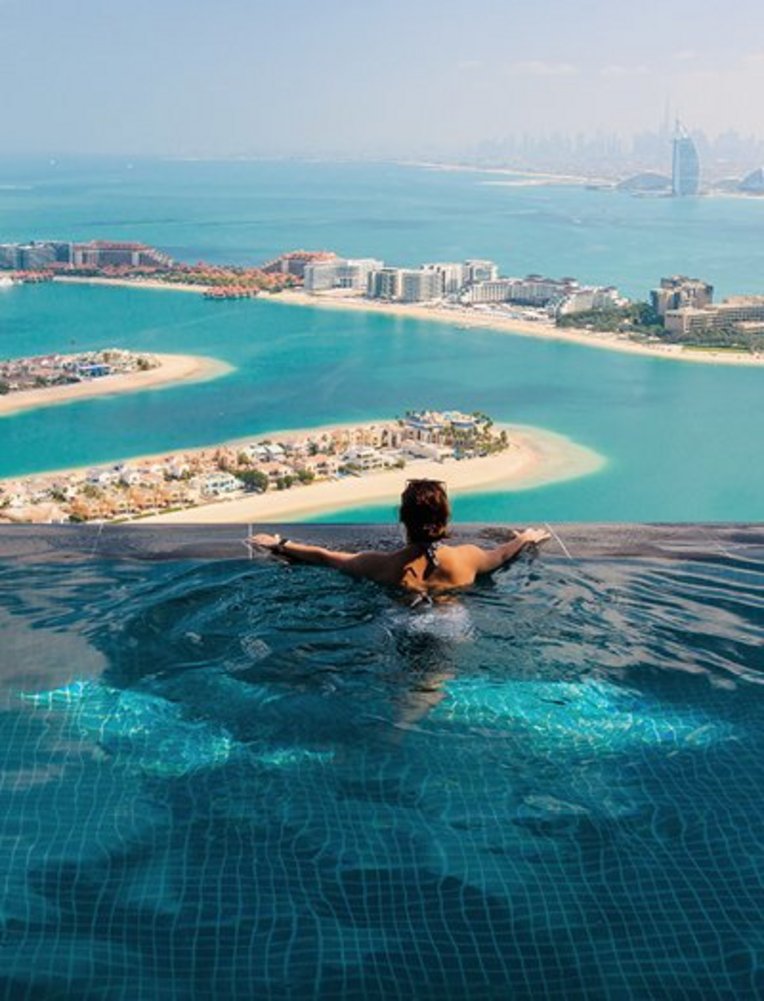 Eine Frau sitzt in einem Pool mit Blick auf den Ozean in Dubai.
