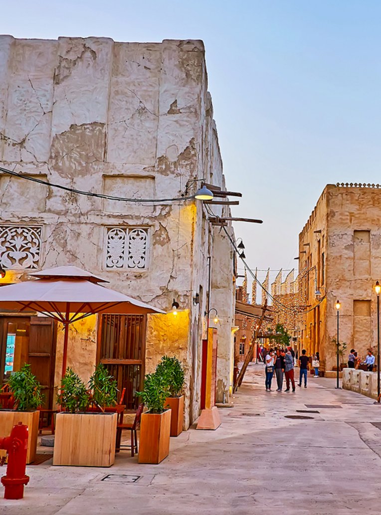 Eine belebte Strasse in Dubai mit Fussgängern und modernen Gebäuden im Hintergrund.