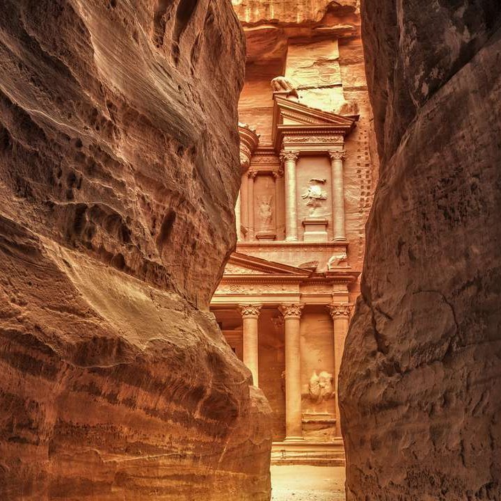 Eingang zur Schatzkammer von Petra in Jordanien, umgeben von beeindruckenden Felsformationen und antiken Strukturen.
