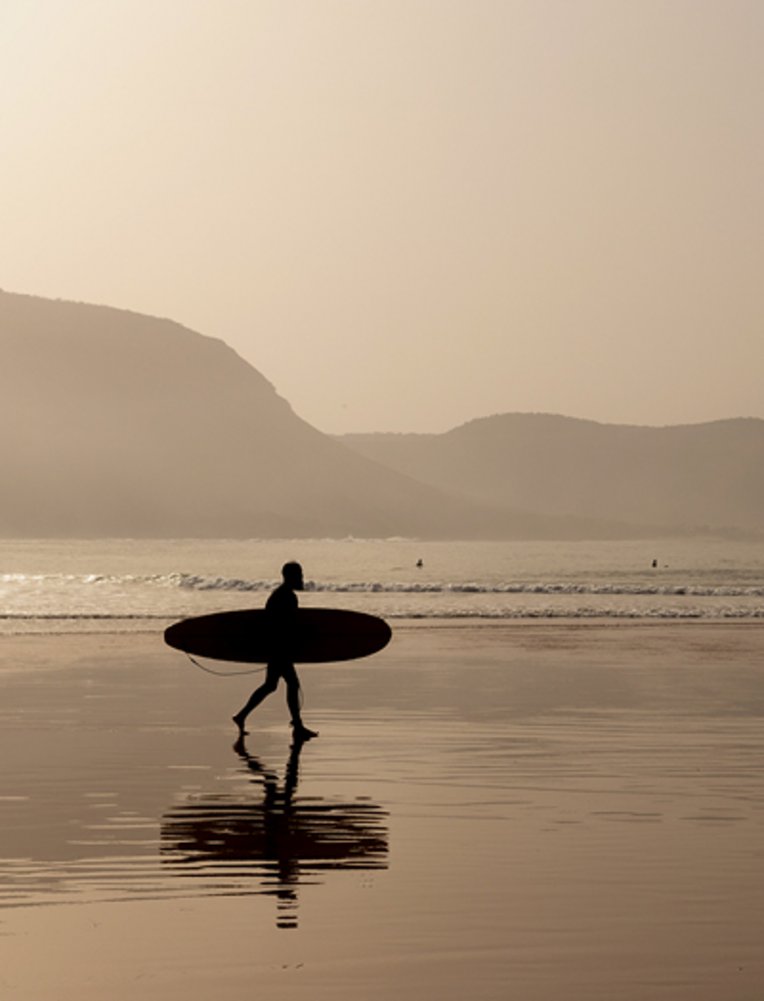Silhouette eines Surfers am Strand bei wunderschönem Sonnenuntergang in Marokko.