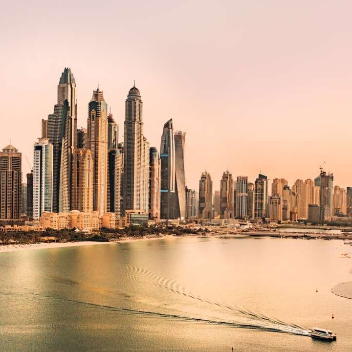 Blick von oben auf die Dubai-Skyline, reflektiert im Wasser, mit modernen Wolkenkratzern und strahlendem Himmel.