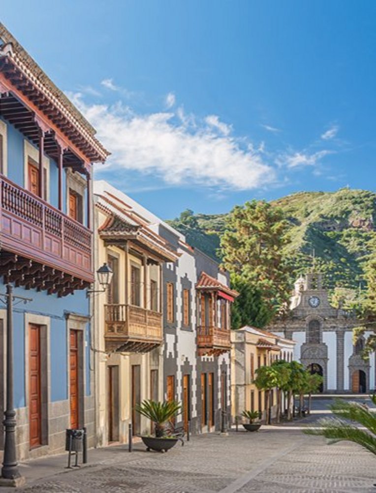 Eine Strasse auf den Kanaren mit einem markanten Uhrturm und einigen umliegenden Gebäuden.