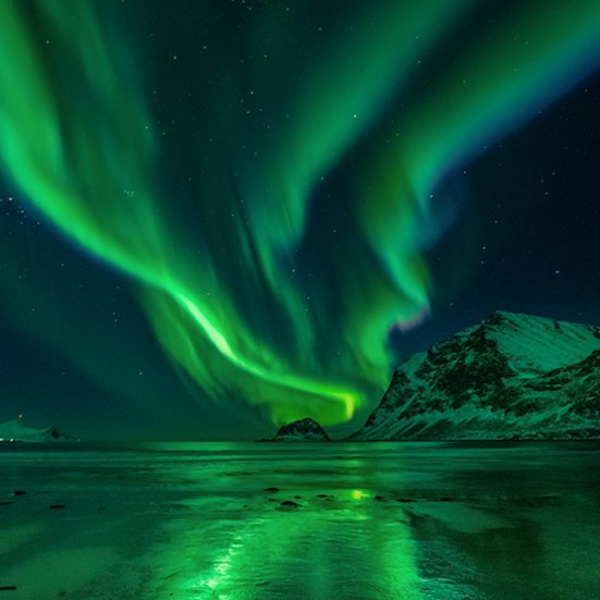Die Nordlichter tanzen über dem Wasser in Island und schaffen ein magisches Lichtspiel.