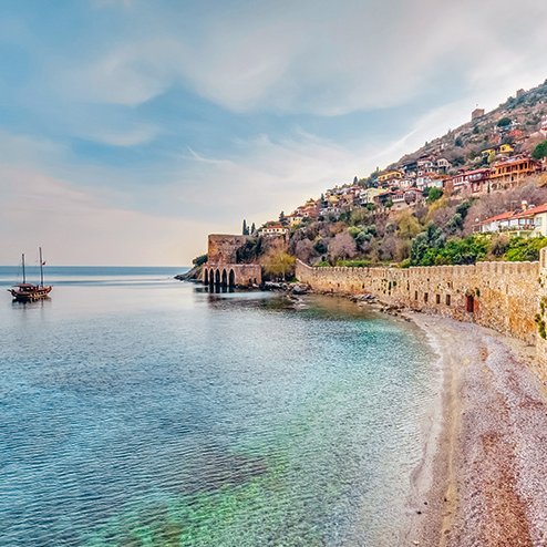 Strand mit felsiger Küste und einem Boot im Wasser, aufgenommen an der türkischen Küste.