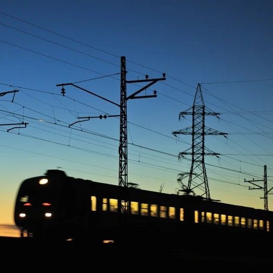 Ein Zug fährt am Abend durch Istanbul, umgeben von Stromleitungen.