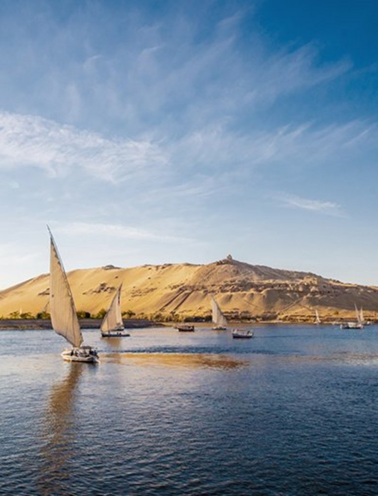  Ein Gewässer mit Booten, die sanft darauf treiben, umgeben von einer ruhigen Landschaft.