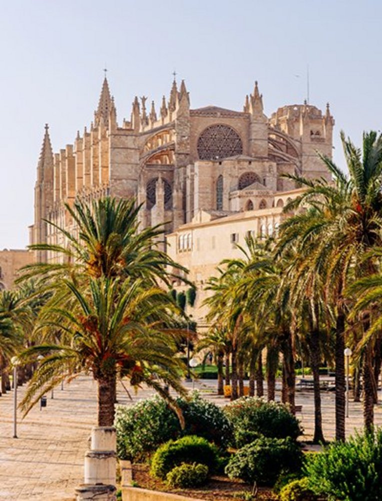 Grosses Gebäude mit einem Uhrturm im Hintergrund, typisch für die Architektur auf Mallorca.