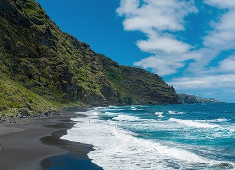 Schwarzer Sandstrand mit Bergen im Hintergrund auf den Kanaren.