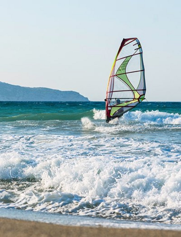 Windsurfer auf dem Wasser vor einem Strand in Kreta.