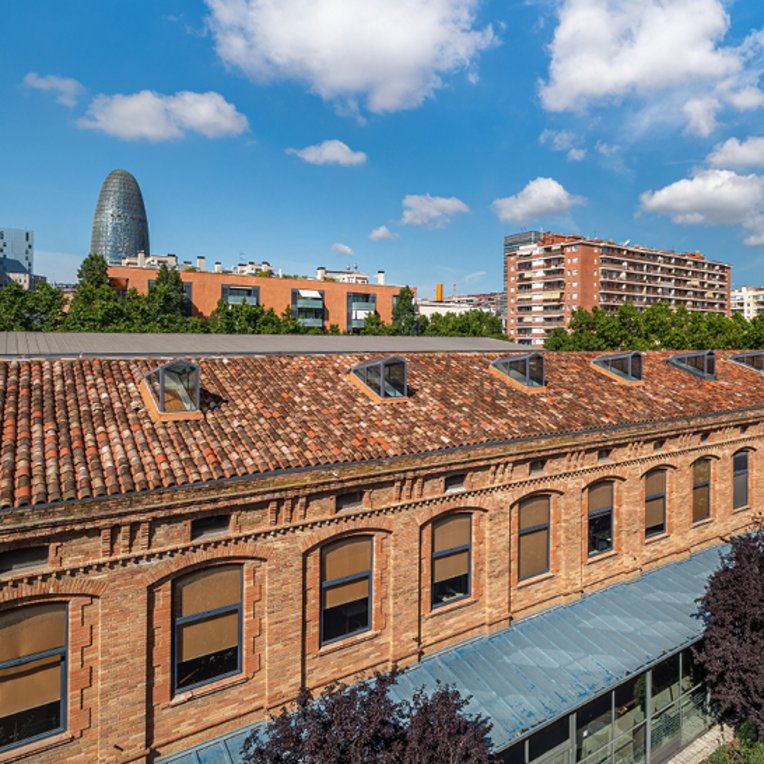 Grosses Gebäude mit einem Uhrturm und einer Uhr, das das Restaurant Barcelona Tapas Poblenou beherbergt.