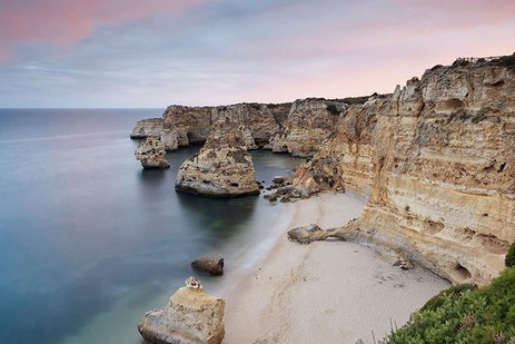 Steilküste mit Sandstrand und beeindruckenden Felsformationen bei Sonnenuntergang.