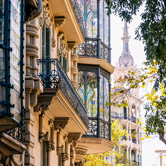 Eine Strasse in Barcelona mit kunstvollen Balkonen und einem markanten Uhrturm.
