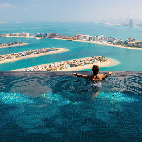 Eine Frau sitzt in einem Pool mit Blick auf den Ozean in Dubai.