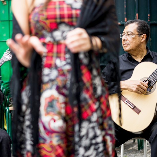 Eine Frau im Kleid spielt Gitarre und singt Fado in Lissabon.