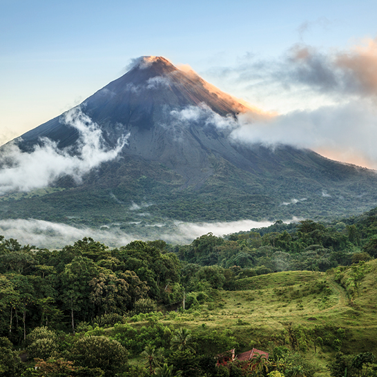 Arenal Vulkan in Costa Rica, umgeben von üppiger Natur und Wolken, die den majestätischen Gipfel umhüllen.