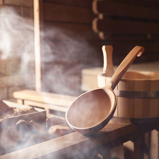 Ein Holzlöffel und eine Holzschüssel liegen auf einem Tisch, passend zur Finnland Saunakultur.