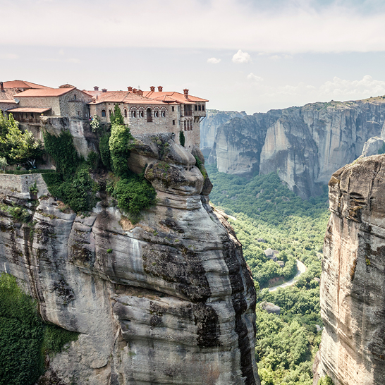 Kloster Meteora, majestätisch auf einer Klippe in Griechenland gelegen, umgeben von beeindruckenden Felsen und grünem Wald.