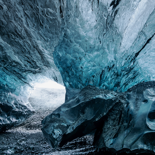 Grosse Eishöhle in Vatnajökull, mit blauem Wasser und Felsen im Inneren.