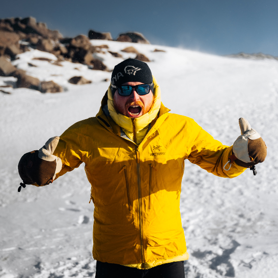 Ein Mann mit einer gelben Jacke steht im Freien.