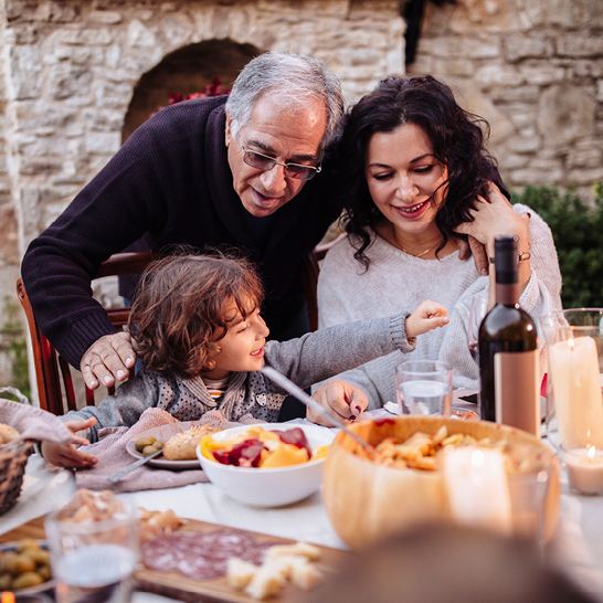 Eine Familie geniesst ein gemeinsames Essen im Freien, umgeben von Natur und fröhlicher Atmosphäre.