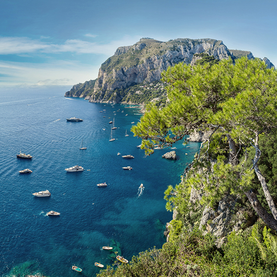 Die Capri-Küste in Italien mit klarem Wasser und beeindruckenden Felsen, umgeben von kleinen Inseln.