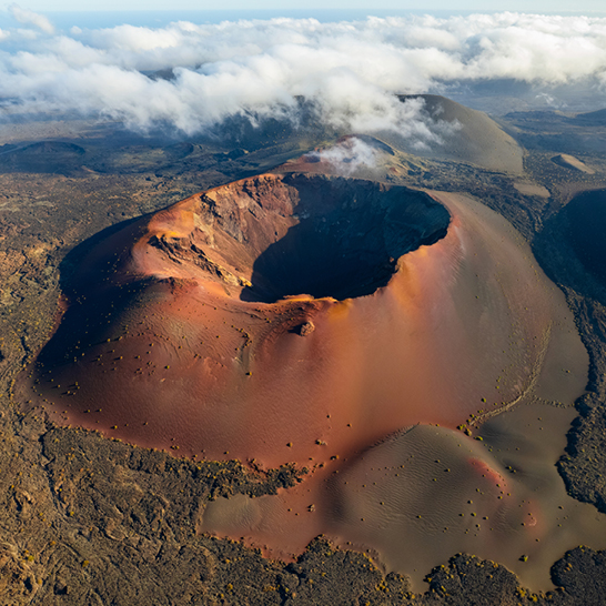 Vue aérienne d'un cratère à Lanzarote, montrant des paysages volcaniques impressionnants et des formations rocheuses.
