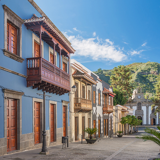 Une rue des Iles Canaries avec une tour de l'horloge et quelques bâtiments colorés en arrière-plan.