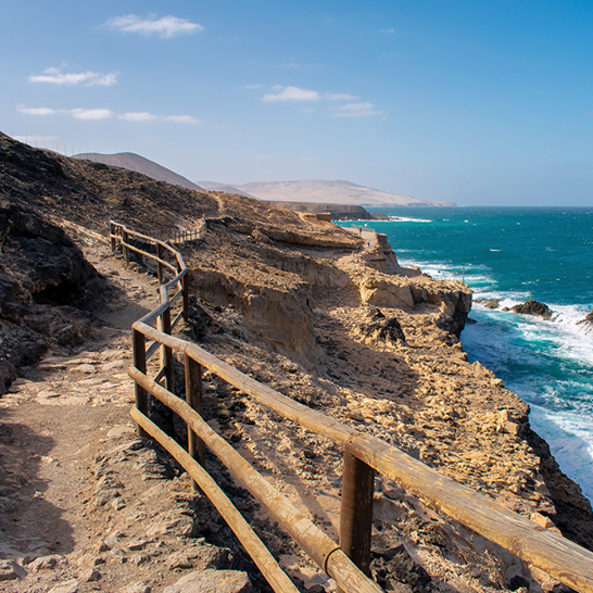 Une clôture en bois au bord d'une falaise, avec une vue sur les paysages des Iles Canaries.
