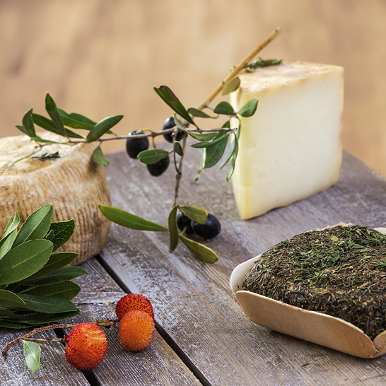 Ein rustikaler Tisch, der mit Käse, Oliven und frischen Beeren dekoriert ist.