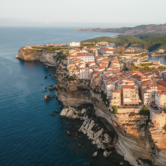 Blick von oben auf eine Stadt auf einer Klippe, die das Meer im Hintergrund zeigt.