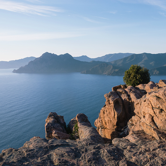 Eine beeindruckende Felswand, die hoch über dem Wasser thront, mit zerklüfteten Kanten und strahlendem Himmel.