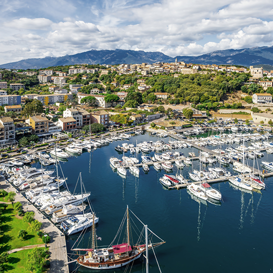 Blick auf eine Marina voller Boote, die friedlich im Wasser liegen, umgeben von malerischer Landschaft.