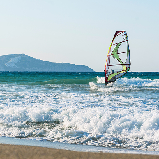 Windsurfer auf dem Wasser vor einem Strand in Kreta.