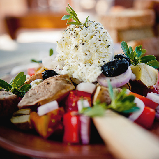 Ein Teller mit mediterranen Gerichten aus Kreta, darunter frisches Gemüse, Oliven und gegrillter Fisch.