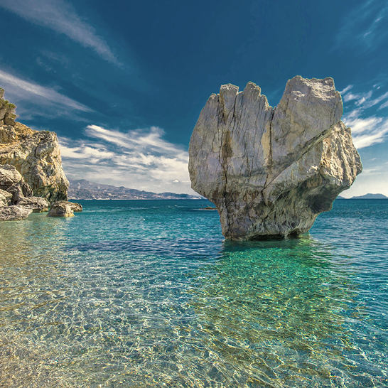 Felsformation im Wasser nahe der Küste von Kreta, umgeben von klarem Blau und sanften Wellen.