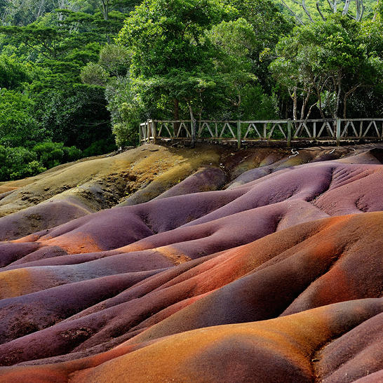 Un pont traversant une colline aux teintes arc-en-ciel.