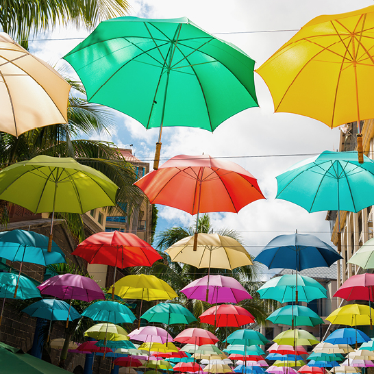 Une rue à l'île Maurice ornée de nombreux parapluies colorés suspendus dans le ciel, créant une ambiance festive.