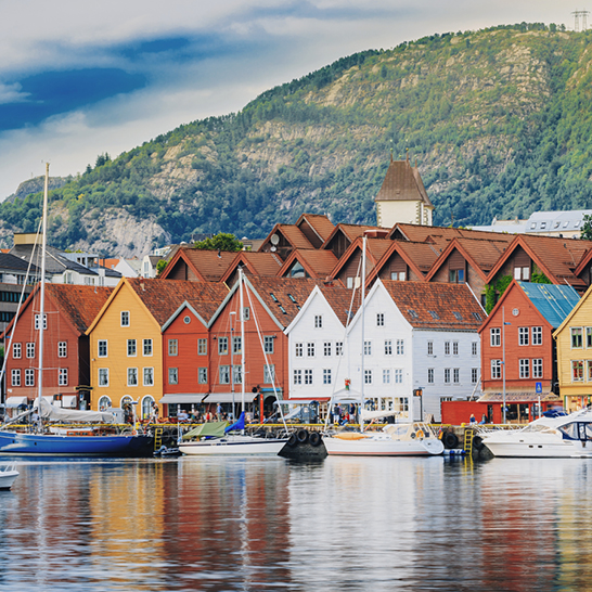 Un port de Bergen avec des bâtiments colorés et des bateaux amarrés, créant une scène vivante et pittoresque.