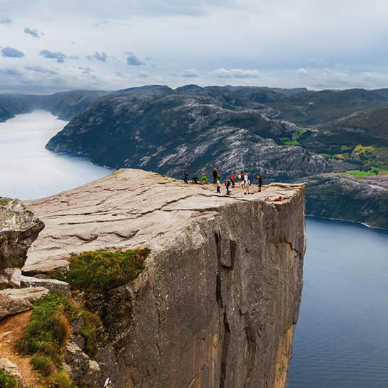 Un groupe de personnes se tient sur une falaise, admirant un vaste plan d'eau à Stavanger.