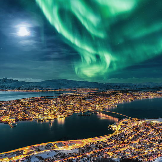 Aurore boréale illuminant la ville de Tromsø, Fjordaland, Norvège, avec des couleurs vives dans le ciel nocturne.
