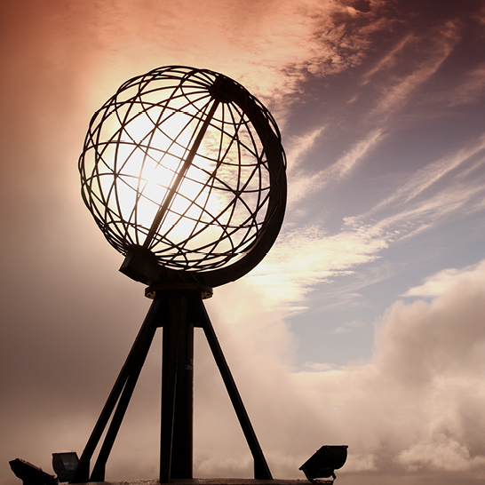 Un globe sur un mât avec le soleil derrière, situé à Nordkap.