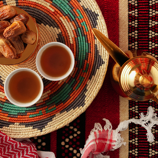 Ein Tisch mit einer Teekanne, Tassen und einem Teller mit Datteln, symbolisiert die Gastfreundschaft im Oman.