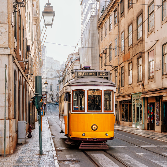 Eine schmale Straße mit einer gelb-weißen Straßenbahn.