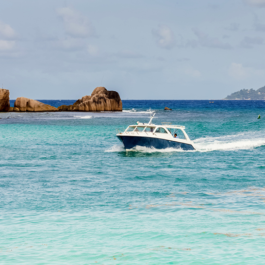 Un bateau navigue sur les eaux cristallines des Seychelles, entouré de paysages tropicaux.