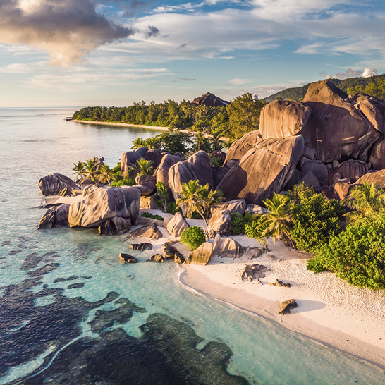 Plage et rochers des Seychelles vus du ciel, avec des vagues douces et un paysage tropical.